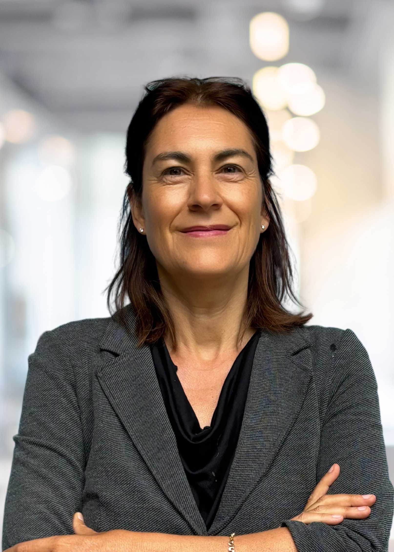 Porträt Tanja Sattele, braune halblange Haare, Brille ins Haar gesteckt, graues Jackett